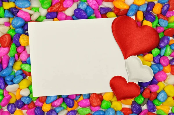 Corazones y tarjeta blanca en guijarros de colores Fotos de stock