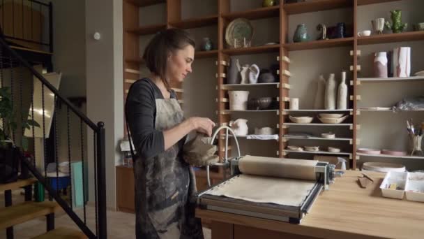 Beautiful female ceramist laying clay uses a device for rolling clay dolly shot — Stock Video