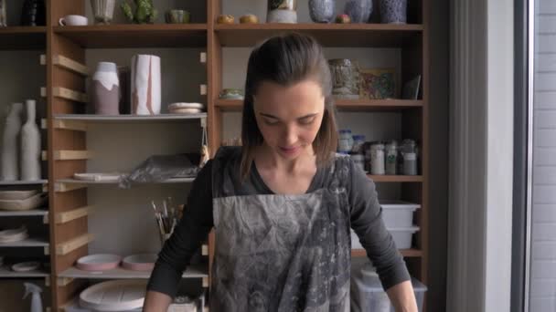 Frau, die mit Ton arbeitet, rollt Ton mit Nudelholz aus — Stockvideo