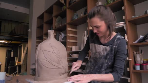 A beautiful woman ceramist removes excess clay from her product dolly shot — Stock Video