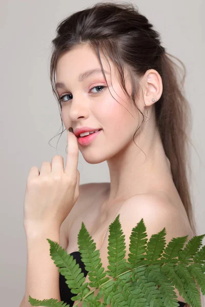 Piękna dziewczyna z liściem paproci, odizolowana na jasnoszare tło, emocje, kosmetyki — Zdjęcie stockowe