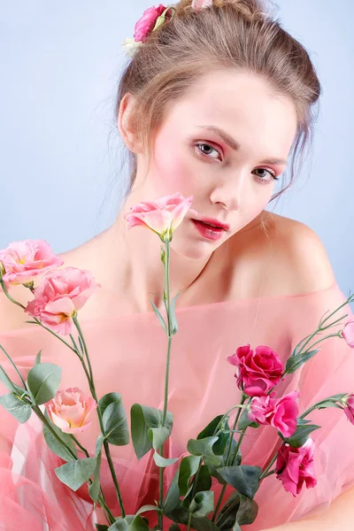 Mooi meisje, geïsoleerd op een blauwe achtergrond met kleurrijke bloemen, emoties, cosmetica — Stockfoto