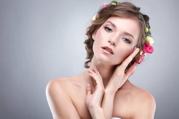 Bella ragazza, isolata su uno sfondo grigio chiaro con fiori varicolore in capelli, emozioni, cosmetici — Foto Stock