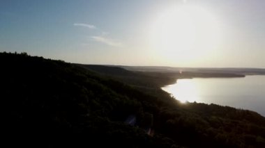 Güneşli bir yaz gününde gün batımında dağlarda bir gölün havadan çekilmiş videosu. Dağlarda sabah akşam