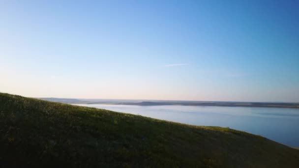 Flygfoto av en sjö i bergen vid solnedgången en solig sommarvarm dag. Morgon eller kväll i fjällen — Stockvideo