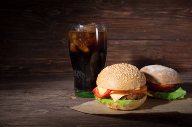 Ahşap zemin üzerinde kola olan iki barbekülü hamburger..