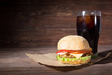 Ev yapımı burger ve ahşap arka planda soğuk içecek kola.