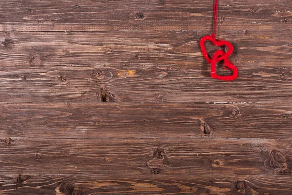 Dvě vlněná láska srdce visí na dřevěném pozadí — Stock fotografie