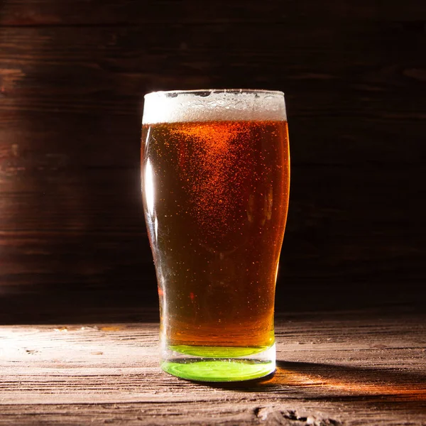 Glass of beer on brown wooden background — Stock Photo, Image