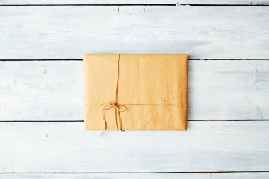 Noel tarzı, iplerle bağlanmış, taşralı, kahverengi kağıt paketi kapat. Beyaz ahşap zemin.