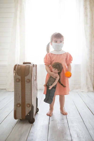 Little cute kid girl in quarantine at home dreams of traveling. . Virus Pandemic Protection Concept