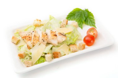 Beyaz arka planda beyaz dikdörtgen tabakta tavuk ve peynirli ev yapımı sebze salatası..