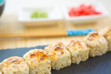 Suşi siyah tahta yüzeyde yuvarlanır. Japon yemeği. Sıcak kızarmış suşi..