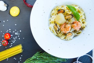 Siyah taş bir masada deniz mahsullü makarna. Üst görünüm.