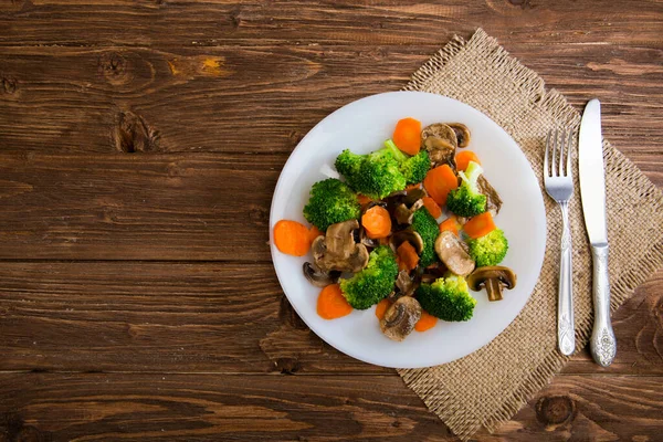 Delicious vegetarian food in a dish vegetable meal. Broccoli, carrots and mushrooms.