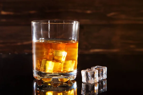 Glas Whisky Met Ijsblokjes Een Zwarte Tafel Tegen Houten Ondergrond — Stockfoto