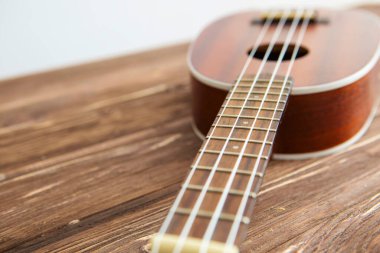 Fotoğraf, ahşap bir masada gitar çalan bir müzik aleti tasvir ediyor.