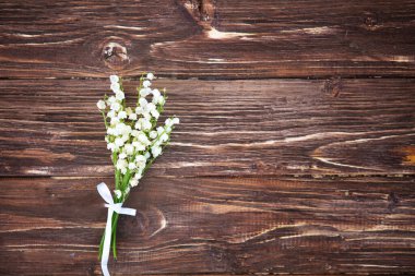 Narin bir kokusu olan harika kokulu beyaz çiçekler. Kahverengi ahşap arka planda vadi zambakları Boşluğu kopyala.