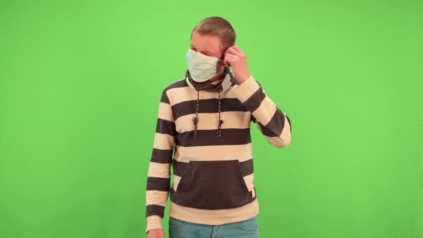 De man zet een medisch masker op een chromakey. Virusbeschermingsgel, ontsmettingsmiddel. Voorkomen van verspreiding van coronavirus covid-19. — Stockvideo