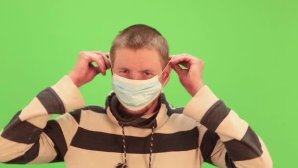 Man puts on medical mask on a chromakey. Virus protection gel, disinfectant. Prevent spread of coronavirus covid-19. — Stock Video