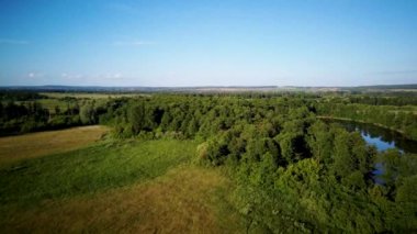 Güneşin batışının ışığında ılık bir yaz gününde gölün havadan çekilmiş videosu.