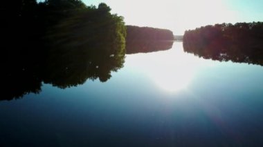 Güneşin batışının ışığında ılık bir yaz gününde gölün havadan çekilmiş videosu.