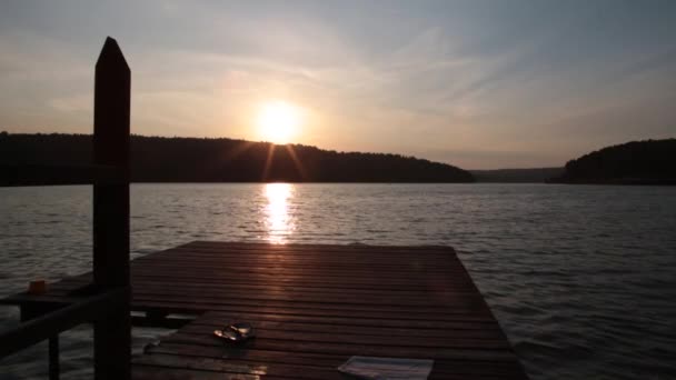 Egy fiú leugrik a mólóról a tengerbe vagy a tóba a hegyekben egy meleg nyári napon. Lassított mozgású videó — Stock videók