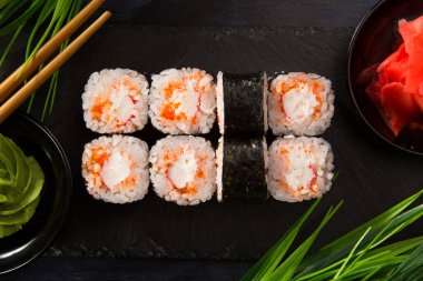 Siyah arka planda wasabi ve zencefilli suşi ruloları. Japon Doğu mutfağı.