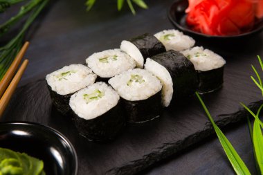 Siyah arka planda wasabi ve zencefilli suşi ruloları. Japon Doğu mutfağı.