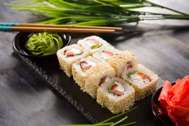 Siyah arka planda wasabi ve zencefilli suşi ruloları. Japon Doğu mutfağı.