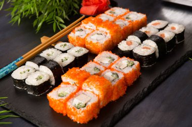 Siyah arka planda wasabi ve zencefilli suşi ruloları. Japon Doğu mutfağı.