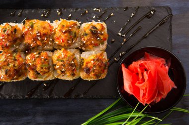 Siyah arka planda wasabi ve zencefilli fırında suşi ruloları. Japon Doğu mutfağı.