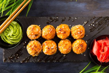 Siyah arka planda wasabi ve zencefilli fırında suşi ruloları. Japon Doğu mutfağı.