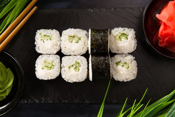 Siyah arka planda wasabi ve zencefilli suşi ruloları. Japon Doğu mutfağı.