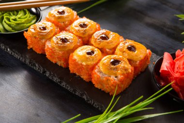 Siyah arka planda wasabi ve zencefilli fırında suşi ruloları. Japon Doğu mutfağı.