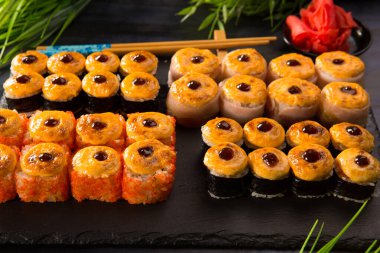 Siyah arka planda wasabi ve zencefilli fırında suşi ruloları. Japon Doğu mutfağı.