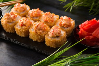 Siyah arka planda wasabi ve zencefilli kızarmış suşi. Japon Doğu mutfağı.