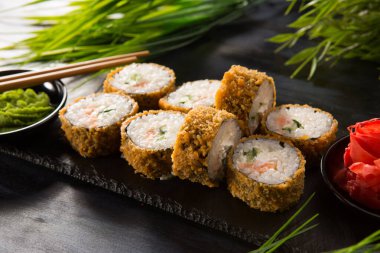 Siyah arka planda wasabi ve zencefilli kızarmış suşi. Japon Doğu mutfağı.
