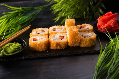 Siyah arka planda wasabi ve zencefilli kızarmış suşi. Japon Doğu mutfağı.