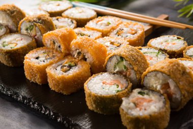 Siyah arka planda wasabi ve zencefilli kızarmış suşi. Japon Doğu mutfağı.