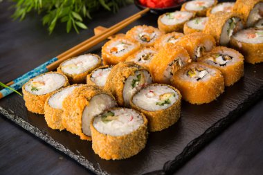Siyah arka planda wasabi ve zencefilli kızarmış suşi. Japon Doğu mutfağı.