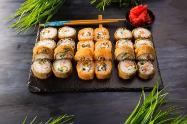 Siyah arka planda wasabi ve zencefilli kızarmış suşi. Japon Doğu mutfağı.
