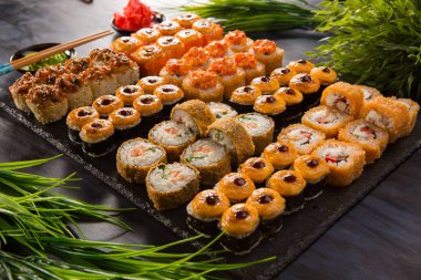 Siyah arka planda wasabi ve zencefilli fırında suşi ruloları. Japon Doğu mutfağı.