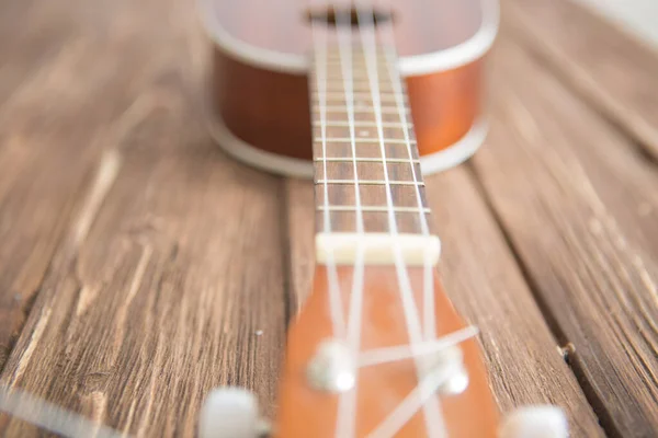 사진은 나무 식탁에 놓인 악기 우쿠 렐레 기타를 묘사하고 있다 — 스톡 사진