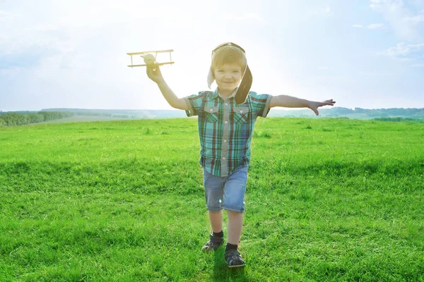 Ξεκινήστε να ταξιδεύετε από την παιδική ηλικία ακόμα και στη φαντασία. χαρούμενο παιδί ονειρεύεται να ταξιδέψει και να παίξει με έναν πιλότο αεροπλάνου σε εξωτερικό χώρο το καλοκαίρι — Φωτογραφία Αρχείου