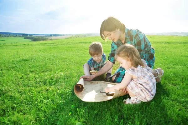 Diese Welt ohne Grenzen. Gehen Sie zu neuen Abenteuern und Entdeckungen. Eine schöne junge Mutter mit ihren Kindern blickt auf eine Weltkarte und entscheidet, wo sie eine Reise machen will — Stockfoto