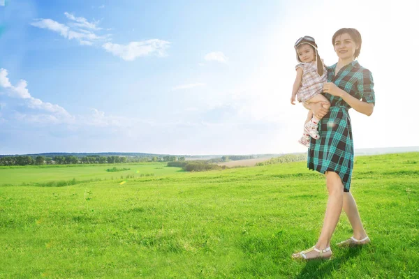 A beautiful mother with a cute daughter is playin on green field — Stock Photo, Image