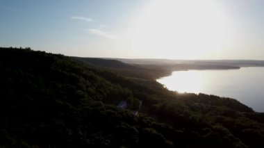 Güneşli bir yaz gününde gün batımında dağlarda bir gölün havadan çekilmiş videosu. Dağlarda sabah akşam