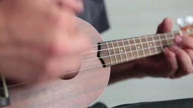 Adam ukulele çalıyor.