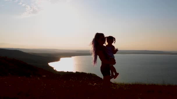 Dívka se svou dcerou si užívá západ slunce na břehu horského jezera. — Stock video